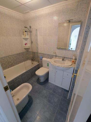 a bathroom with a sink and a toilet and a tub and a sink at Aguamarina, las Calitas, frente al mar in Orihuela Costa