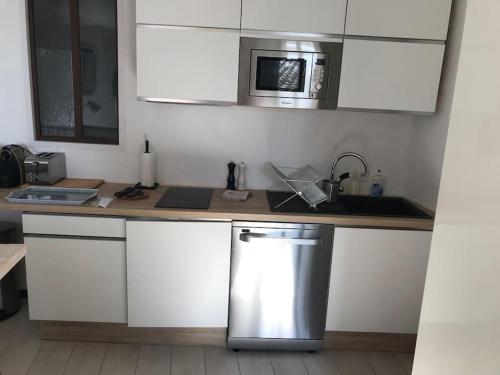 a kitchen with a counter with a sink and a microwave at emplacement idéal, vue mer, parking offert in Sanary-sur-Mer