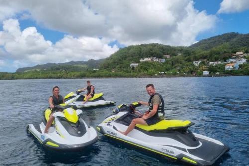 a group of people riding on jet skis in the water at Apt T1,bien situé Anse Mitan Trois Ilets in Les Trois-Îlets