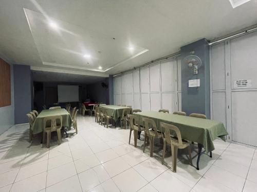 a room with green tables and chairs and a screen at A and A Bed and Breakfast Inn powered by Cocotel in Legazpi