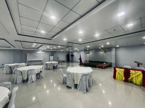 um quarto com mesas e cadeiras brancas e um sofá em A and A Bed and Breakfast Inn powered by Cocotel em Legazpi