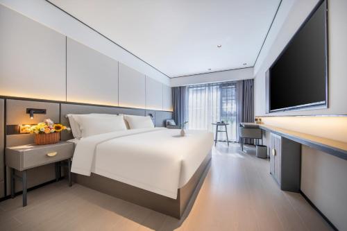 a bedroom with a large white bed and a television at Gongxili - Xige Hotel in Chengdu