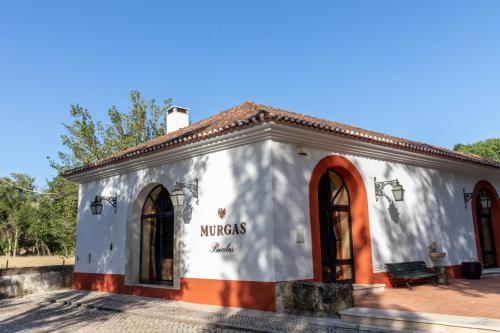 a white and orange building with a bench in front at Quinta das Murgas in Bucelas