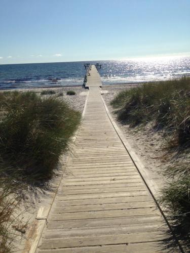 a wooden path leading to the ocean on a beach at Höllviksnäs möten mat logi in Höllviken