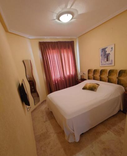 a bedroom with a white bed and a window at Aguamarina, las Calitas, frente al mar in Orihuela Costa