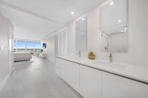 a white bathroom with two sinks and a mirror at Blooming Sun Direct Ocean View in Miami