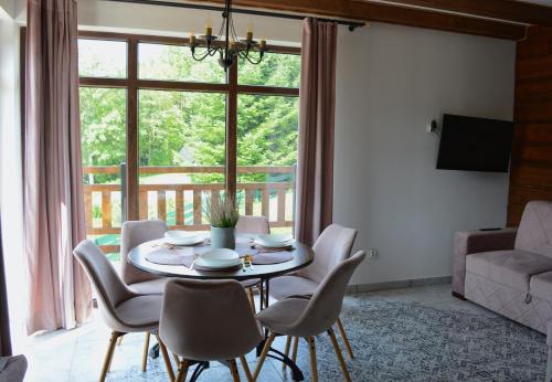 a table and chairs in a living room with a window at Apartamenty Wilcza Knieja in Zawóz