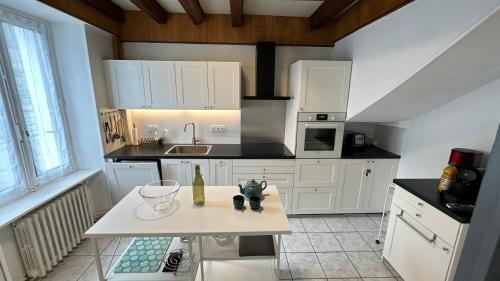 a kitchen with white cabinets and a table in it at Villa Stella 8pers. La Bourboule in La Bourboule