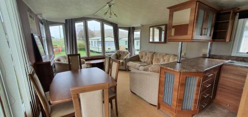 a kitchen and living room with a couch and a table at Honey Cottage Caravan Park in Selkirk