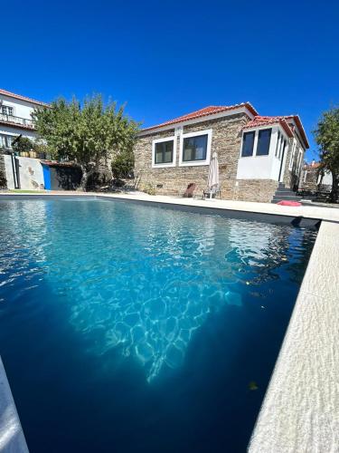 a swimming pool with blue water in front of a house at Domus Vila Maria Douro in Castanheiro do Sul