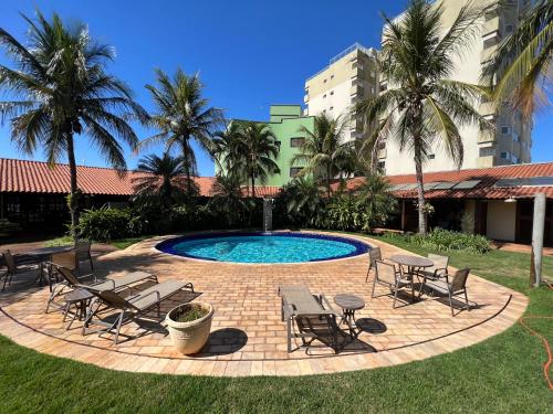 einen Pool mit Stühlen, Tischen und Palmen in der Unterkunft Premier Garden Hotel in José Bonifácio