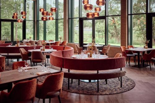 a restaurant with tables and chairs and windows at Van der Valk Hotel Sneek in Sneek