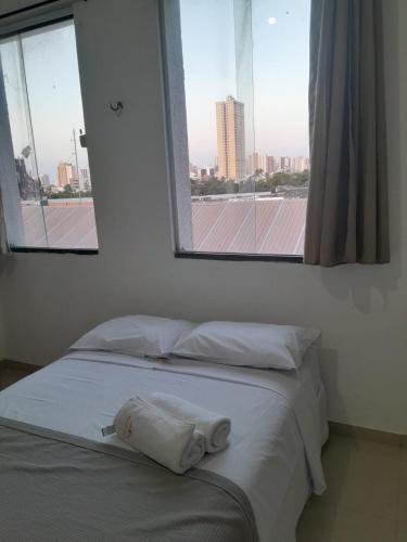 a bed with a towel on it in a room with a window at Central Palace Hotel in Fortaleza