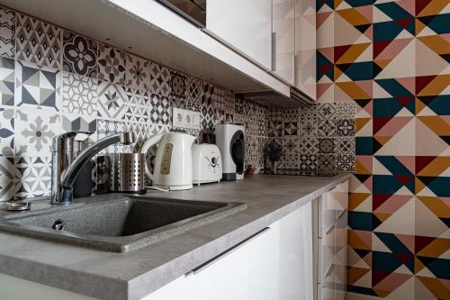 a kitchen with a sink and a mosaic wall at Glam Downtown Apartments in Budapest