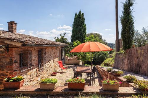a patio with an orange umbrella and chairs and a table at CasaMoira in Trequanda