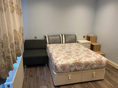 um pequeno quarto com uma cama e um sofá em Ruislip Guest House em Ruislip