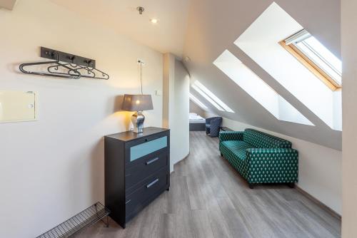 a attic room with a green chair and a dresser at Minimino hotel in Prague