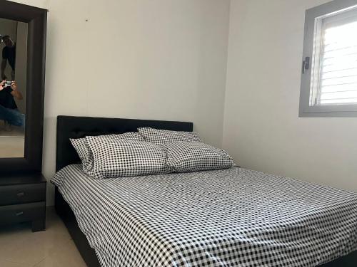 1 dormitorio con 1 cama con manta a cuadros en blanco y negro en Costa residence, en Ashdod
