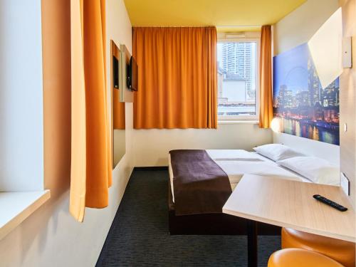 ein Hotelzimmer mit einem Bett, einem Tisch und einem Fenster in der Unterkunft B&B HOTEL Frankfurt-Hbf in Frankfurt am Main