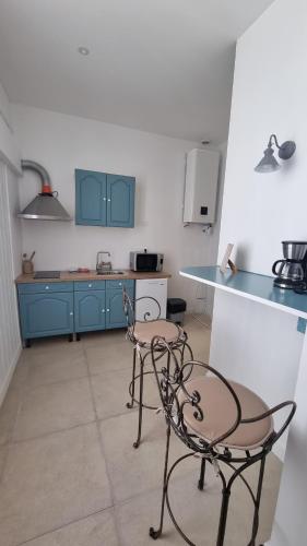 une cuisine avec des placards bleus, 2 chaises et un comptoir dans l'établissement Appartement calme centre ville à 80m des Halles, à Narbonne