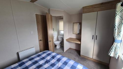a bedroom with a bed and a bathroom with a toilet at Madaisy in Lossiemouth