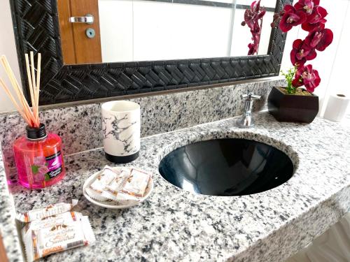 a bathroom counter with a sink and a mirror at APARTAMENTO SOPHIA I - ORLA da PRAIA GRANDE in Arraial do Cabo