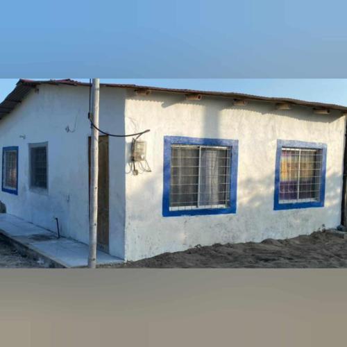 a white building with blue windows and a chair at Casa Ayangue in Santa Elena