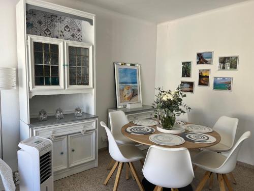 a dining room with a table and white chairs at appartement ideal centre historique in L'Escala
