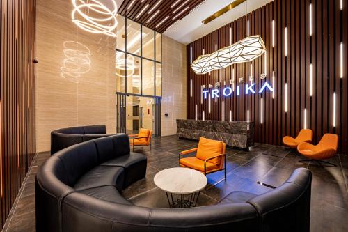 a lobby with a leather couch and orange chairs at One Bedroom Troika Residence Suite 22-10 in Kota Bharu