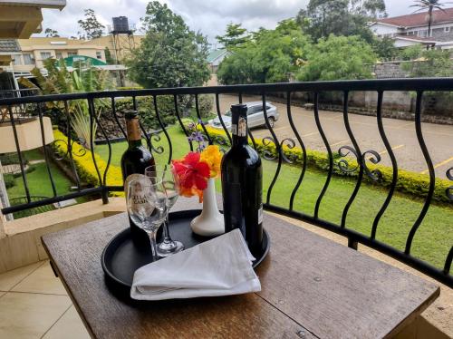 Longview Suites Hotel في نيروبي: طاولة مع زجاجتين من النبيذ وكوب