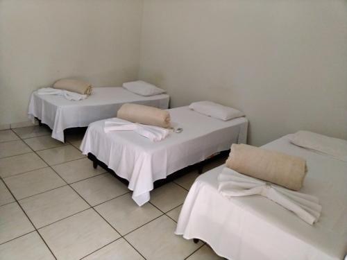 three beds in a room with white walls at GRAN HOTEL in Três Lagoas