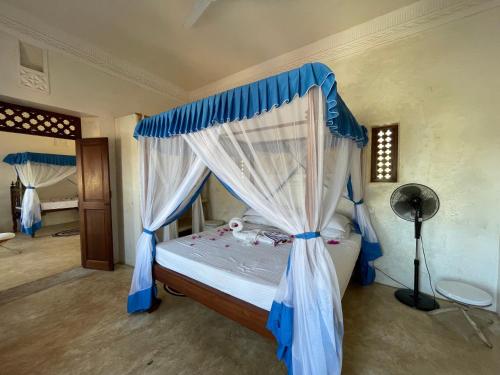 sypialnia z łóżkiem z niebieskim baldachimem w obiekcie Swahili Dreams Apartments w mieście Lamu