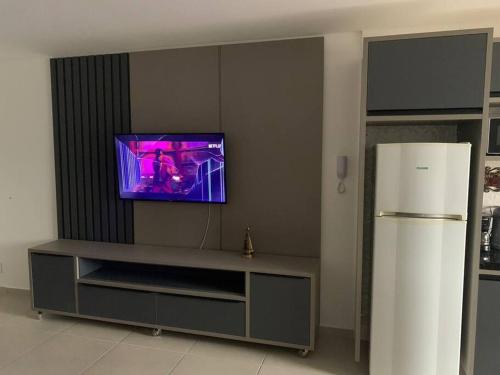 ein Wohnzimmer mit einem Fernseher an der Wand in der Unterkunft Alto Padrão Tenório 2suites com ar, wifi e piscina in Ubatuba