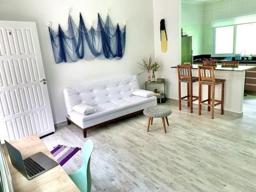 ein Wohnzimmer mit einer weißen Couch und einer Küche in der Unterkunft Casa Maré Mansa: in Bertioga
