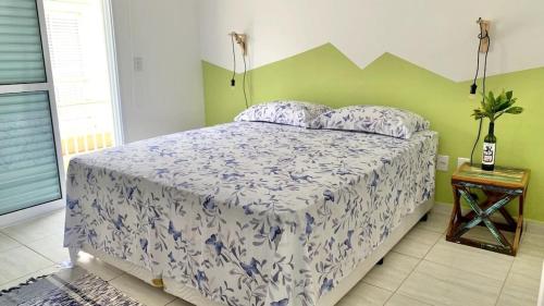 Schlafzimmer mit einem Bett mit einer weißen und blauen Bettdecke in der Unterkunft Casa das Marés: 100M Praia da Enseada - Tranquila e Completa in Bertioga