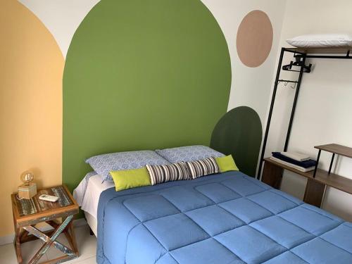 a bedroom with a blue bed and a green wall at Apto Moderno e Completo a 50m da Praia in Bertioga