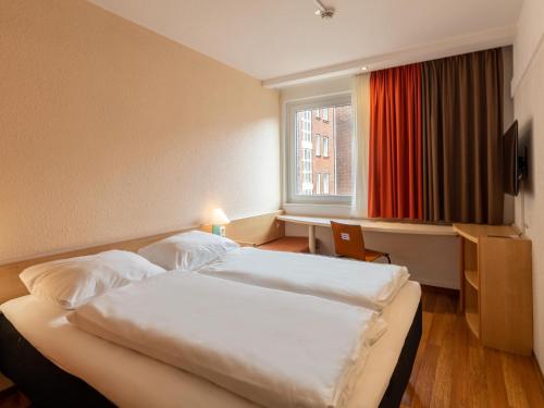 a hotel room with two beds and a window at B&B Hotel Duisburg Hbf-Nord in Duisburg