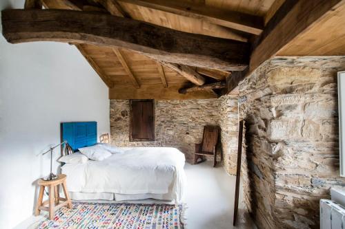 um quarto com uma cama e uma parede de pedra em Casa de las Flores / Casa de campo LUGO em A Pontenova