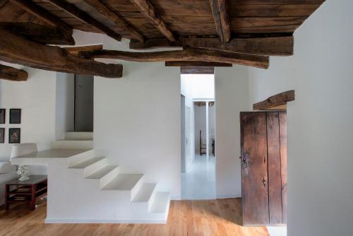 a staircase in a room with white walls and wooden ceilings at Casa de las Flores / Casa de campo LUGO in A Pontenova