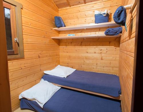 a small room with a bed in a wooden cabin at Camping de Tauves in Tauves