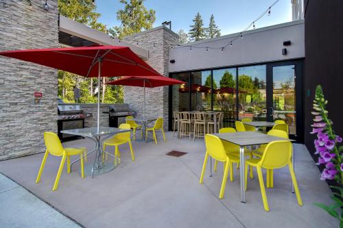 a patio with tables and chairs and a red umbrella at Home2 Suites By Hilton Marysville in Marysville
