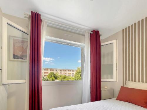 a bedroom with a bed and a window with red curtains at Le Petit Melun in Melun