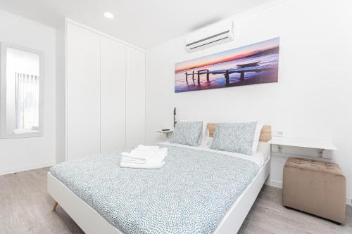 a white bedroom with a bed and a painting on the wall at Príncipe Apartamentos e Suites in Lisbon