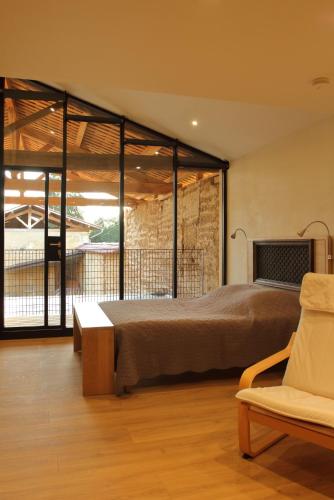 a bedroom with a large bed and a chair at La ferme de Berlioz in La Côte-Saint-André