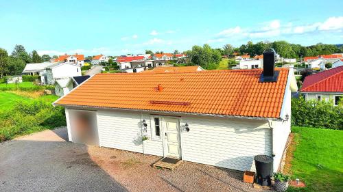a small white house with an orange roof at Boende - Stuga nära naturen, 3 km till Motala centrum, elbilsladdning finns på tomten - privat värd in Motala