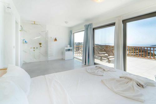 a bedroom with a white bed and a balcony at Sea View Flat with Terrace 3 min to Beach in Gumusluk