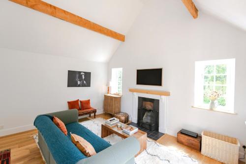 - un salon avec un canapé bleu et une cheminée dans l'établissement Beautiful 3BD Thatched Stone Cottage Kettering, à Pytchley