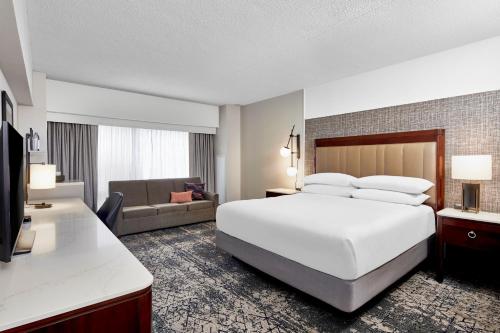 Habitación de hotel con cama blanca grande y sofá en Sheraton Indianapolis Hotel at Keystone Crossing, en Indianápolis