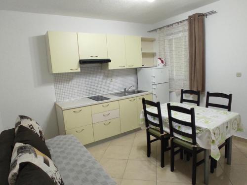 a kitchen with a table and chairs and a kitchen with white cabinets at Apartmani Erlic in Turanj