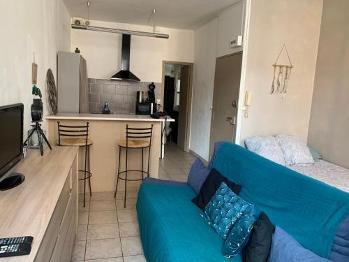 un salon avec un canapé bleu et une cuisine dans l'établissement Studio en plein centre, à Carcassonne